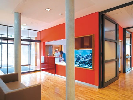 Am bordeauxroten Empfangstresen begrüßen die Krankenschwestern die Familien....