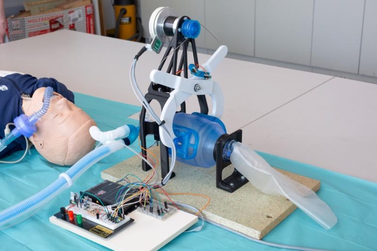 Das Beatmungsgerät besteht aus einem Motor, der über zwei Hebel (weiß)...